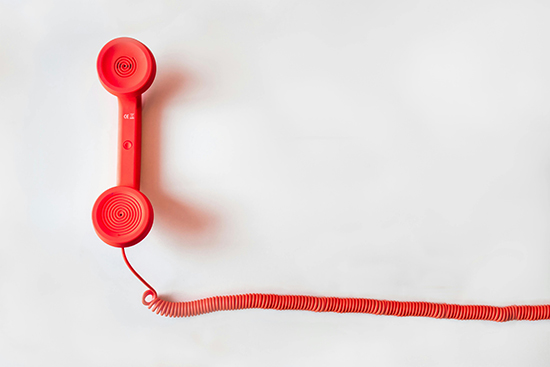 Red telephone handset on a plain background