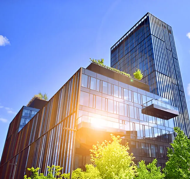 Glass office building with rooftop greenery and surrounding trees